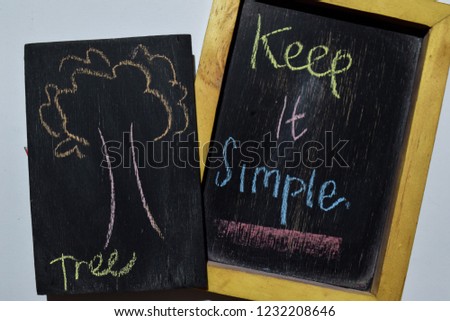 Keep it Simpe on phrase colorful handwritten on blackboard, tree with white background. Education concept Royalty-Free Stock Photo #1232208646