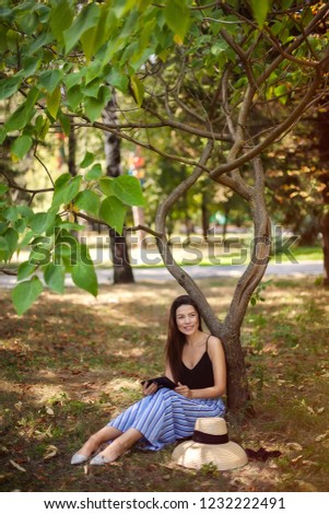 girl with a tablet in nature sits under a tree, Work anywhere, in nature. vertical photo.