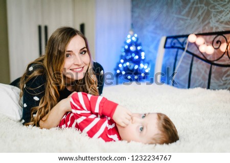 Portrait of happy mother and son celebrate Christmas. New Year's holidays. Toddler with mom in the festively decorated room with Christmas tree and decorations.