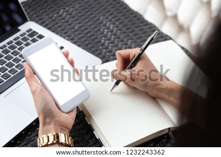 mockup image of cell phone.Businessman work at workplace Think business investment plan.Contact Investor using phone.make note of appointment information in the notebook.design creative work space
