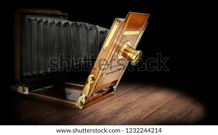 Beautifully crafted, vintage wood and brass studio camera on dark rustic wooden background.