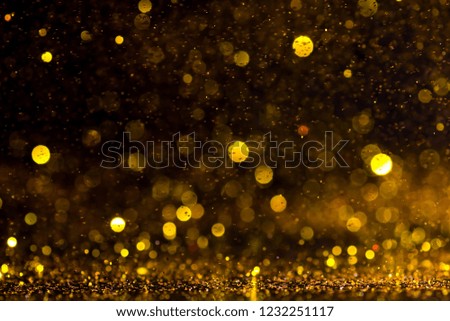 Sparkling gold glitter powder on black background.
Orange and Yellow diamond silver sparkle glitter for texture background.
Sprinkle dust golden light Christmas and  happy new year. 