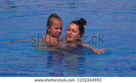 Woman with child  swim together in the pool in sunny day