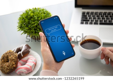 female hand holding touch phone with app personal assistant on screen above the table in cafe Royalty-Free Stock Photo #1232265199