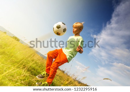 Boy playing football in a meadow, having fun