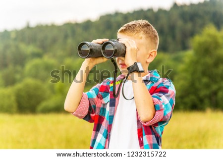 Young boy looking through binoculars, outdoors