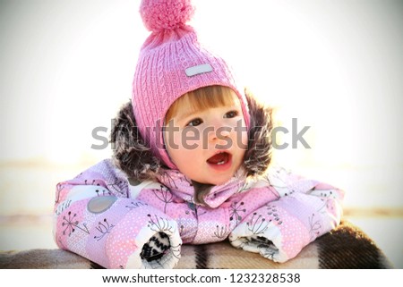 child outside on the field in winter in warm clothes