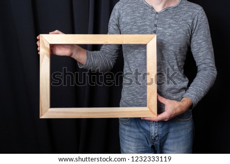 A man holds in his hands a rectangular wooden subframe for stretching canvas