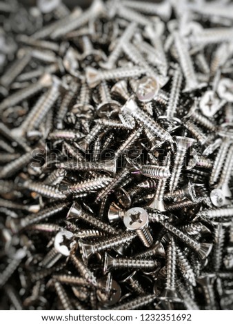 Many chrome screws for construction, close up and selective focus