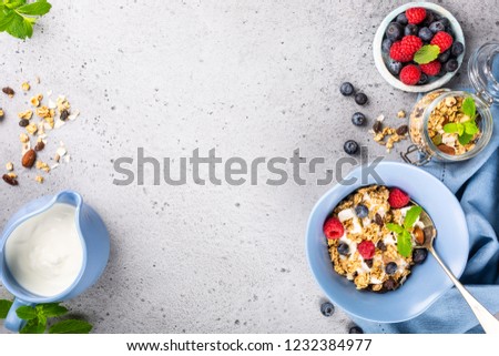 Healthy food background with homemade oatmeal granola or muesli with yogurt and fresh berries for healthy morning breakfast, top view, copy space.