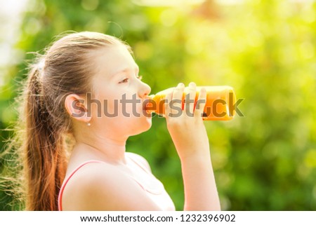Portrait of a young girl drinking a bottle of juice
