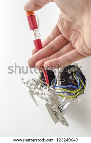 Closeup of an electrician testing electric voltage on a light switch.