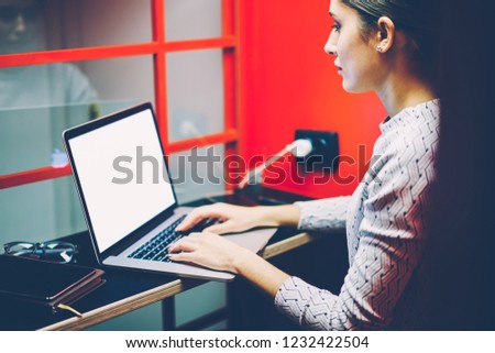 Serious female manager typing on laptop computer with mock up screen making preparation for making skype conference in cabin,woman keyboarding on netbook waiting for video call in noise insulance box Royalty-Free Stock Photo #1232422504