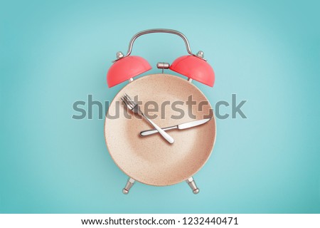 Alarm clock and plate with cutlery . Concept of intermittent fasting, lunchtime, diet and weight loss Royalty-Free Stock Photo #1232440471