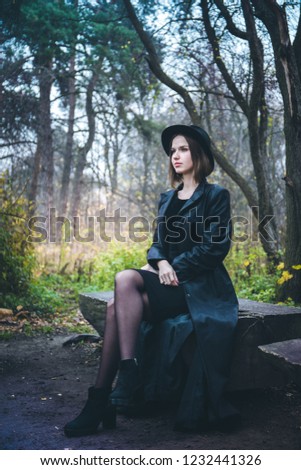 girl in a black coat sitting on a wooden bench