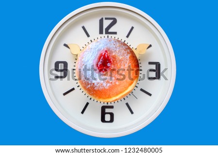 Hanukkah time. Clock with candles instead of arrows and tasty Jelly Doughnuts with jam. Chanukah celebration concept.