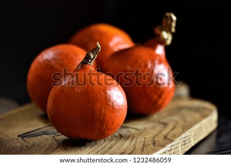 ripe orange shiny, pumpkins Hokkaido, on a wooden board on a black background
