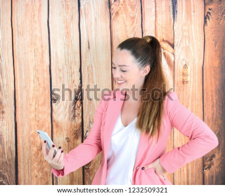 Happy business woman holding a mobile phone against a wooden background