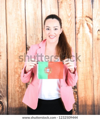 Happy business woman smiling while holding the flag of Portugal against a wooden background
