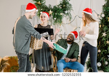 Picture showing group of friends celebrating Christmas at home and exchanging christmas gifts.