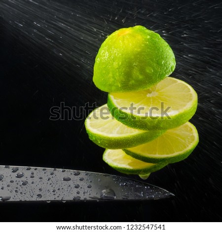 Green lemon cut on the fly, water spray.