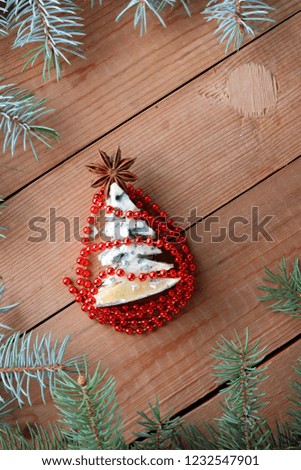 Christmas cheese with red decorations on wooden boards. Spruce branches on wooden background. Fir tree made of cheese and anise. Festive pattern, top view