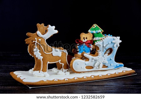 Christmas gingerbread sleigh with deers on a wooden surface on a black background.