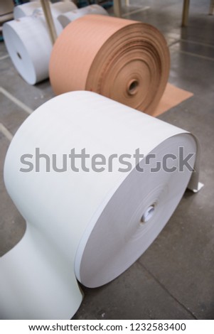A beautiful smooth clean paper roll, continuous sheet of white freshly made paper for painting, wallpaper and wrapping. Industrial paper roll folds on industrial machinery.