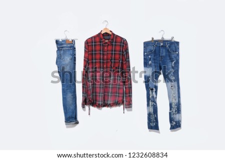 Blue denim torn jeans with blue shirt ,cotton plaid shirt, rack isolated
