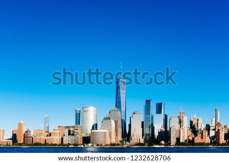 View of the skyline of downtown Manhattan over Hudson River under blue sky, at sunset, viewed from New Jersey, in New York City, USA