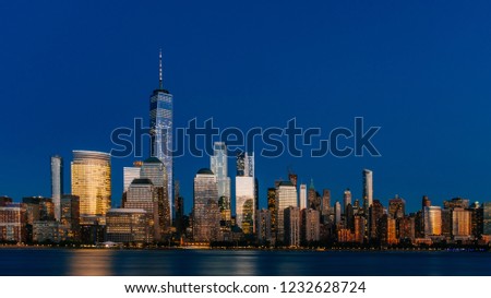 Night view of skyline of downtown Manhattan over Hudson River under dark blue sky, viewed from New Jersey, in New York City, USA