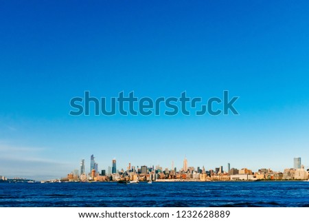 View of the skyline of uptown Manhattan over Hudson River under blue sky, at sunset, viewed from New Jersey, in New York City, USA