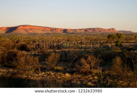 Larapinta Drive snakes its way through the landscape during sunset over George Gills Range near Kings Canyon, Northern Territory, Australia.