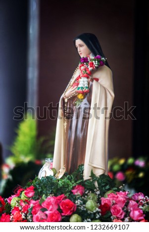 Saint Therese of Child Jesus statue with Thai traditional jasmine garland and pink roses. Picture for art and religion.