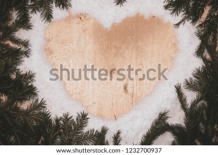 heart of snow with spruce branches on a wooden background, Christmas composition, free space in the center