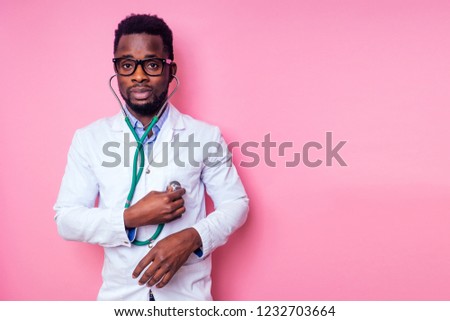 happy male african medical surgeon cardiologist doctor in a white coat on a pink background in the studio.