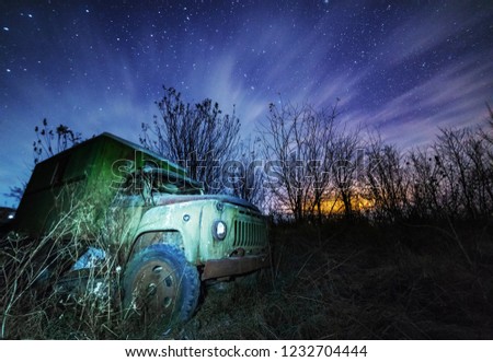 An ancient truck at the top of the mountain for transportation of coniferous forest is illuminated by a photographer of various lights in the moonlit night in the Carpathians as an art object
