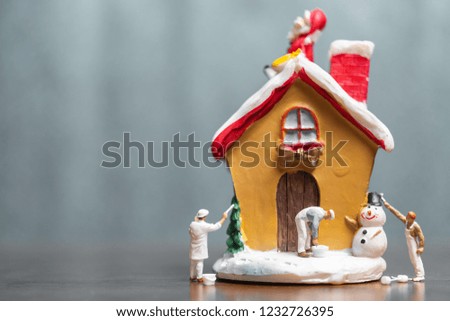 Miniature people painting house and Santa Claus sitting on the roof , Merry Christmas and happy holidays concept.