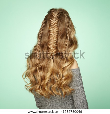 Blonde Girl with Long and Shiny Curly Hair. Beautiful Model Woman with Curly Hairstyle. Care and Beauty Hair Products. Lady with braided hair