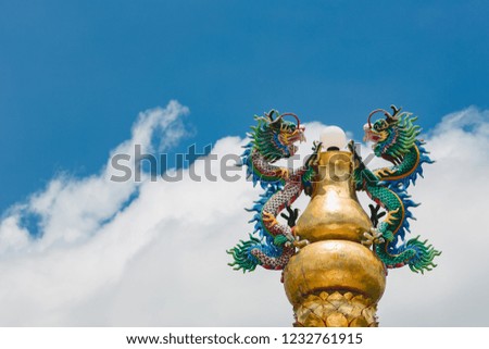 The dragon statue holds the lamp on the top of the pillars with a sky background and a cloud