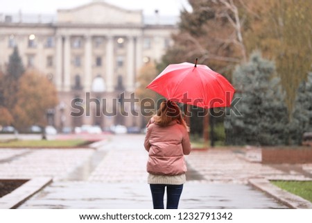 Woman with umbrella in city on autumn rainy day