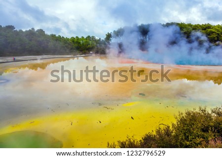 The magic country of hot waters is Wai-O-Tapu. Picturesque lake of multicolored thermal waters evaporates in the air. New Zealand, North Island. The concept of active and phototourism