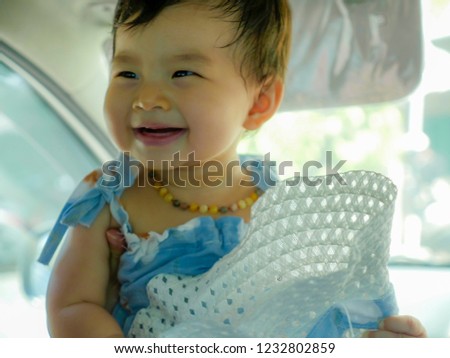 close up isolated face portrait of sweet and adorable Asian Korean baby girl laughing and smiling cheerful holding hat enjoying playful looking cute in infant lifestyle concept
