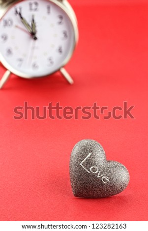 Conceptual image of heart with clock in background. Extreme shallow depth of field with selective focus on foreground.