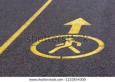 yellow sign on asphalt. footpath with directional arrow
