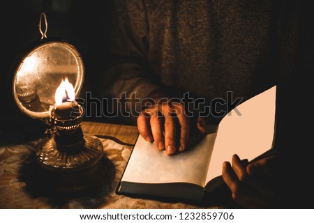 male holding book and oil lamp is near