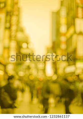 blurred image soft yellow tone of people walking in town for background