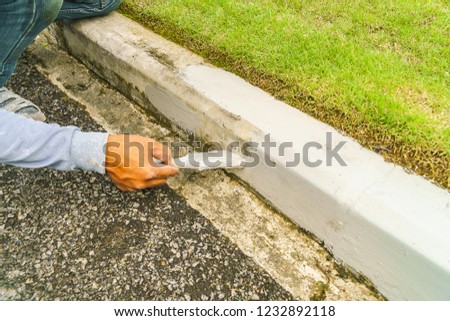 Construction workers painted concrete edges on the road for beauty, hand with trowel and brick.