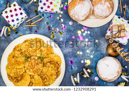 Jewish holiday Hanukkah background. Traditional dishes - sweet doughnuts and potato latkes. Hanukkah table setting on blue background. Copy space