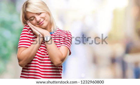 Young beautiful blonde woman over isolated background sleeping tired dreaming and posing with hands together while smiling with closed eyes.
